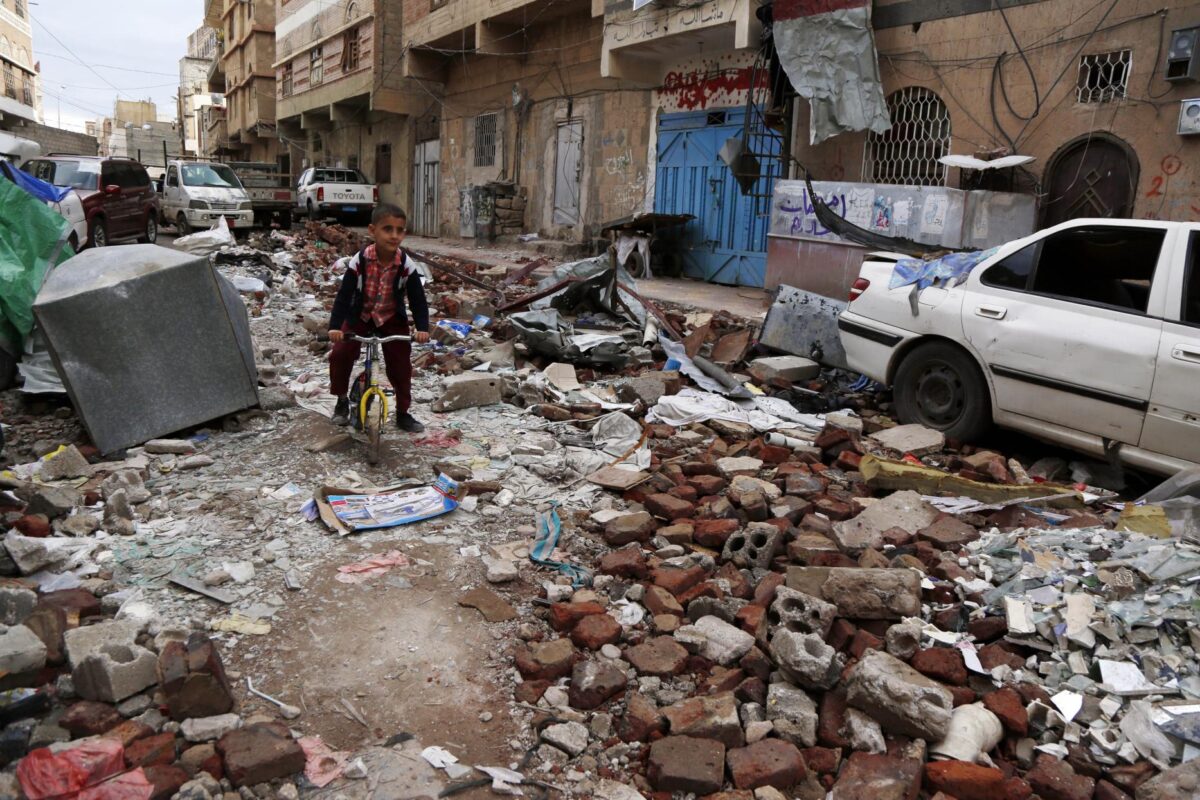 Menino iemenita anda de bicicleta entre escombros de casas destruídas por  recente ataque aéreo realizado da coalizão liderada pelos sauditas.  Em 23 de maio de 2019, Sanaa, Iêmen [Mohammed Hamoud / Getty Images]