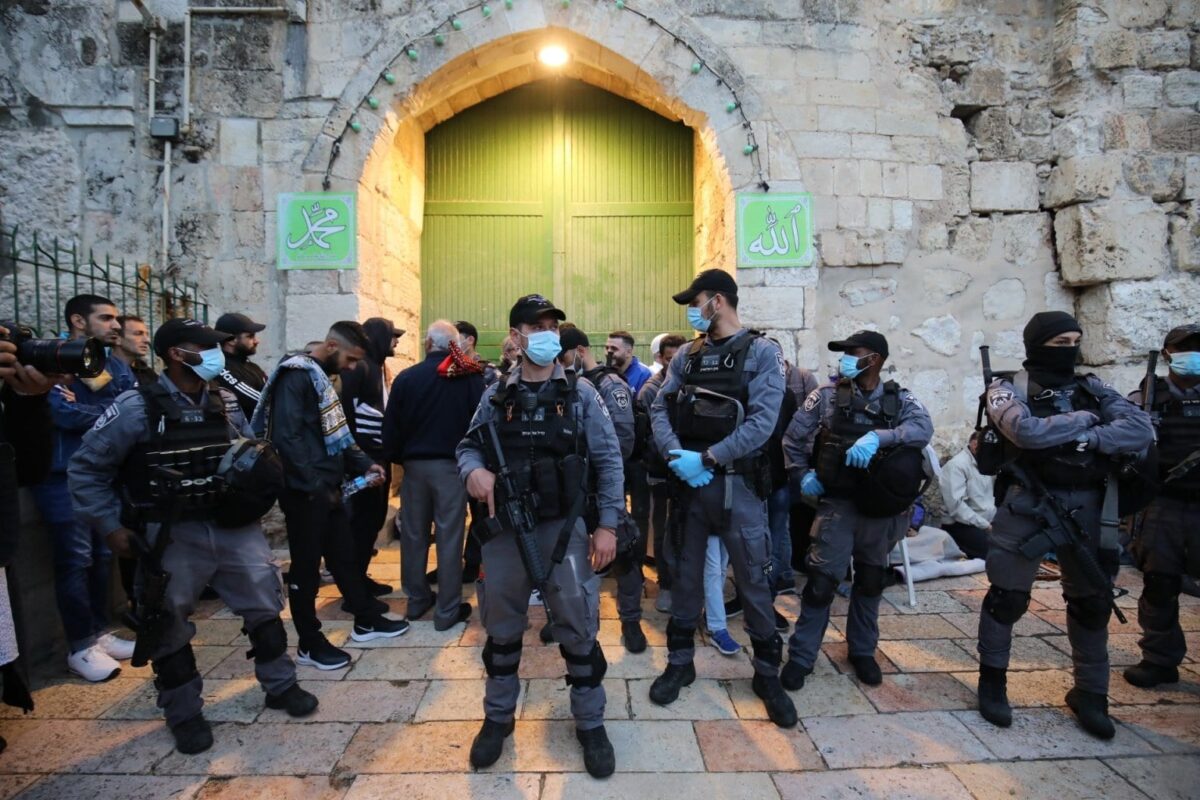A polícia israelense fica de guarda em frente às portas enquanto os muçulmanos palestinos se reúnem para realizar a oração do Eid al-Fitr na mesquita Al-Aqsa, que é fechada como precaução contra a nova pandemia de coronavírus (COVID-19) em Jerusalém 24 de maio de 2020. [Mostafa Alkharouf/Agência Anadolu]