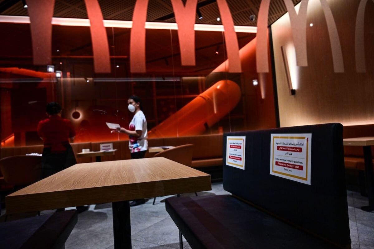 Aviso colocado em um banco de restaurante de fast-food do McDonald's em Dubai, solicita em árabe e inglês que os clientes não se sentem, em respeito ao distanciamento social destinado a impedir a propagação do coronavírus [Giuseppe Cacace/ AFP via Getty Images]