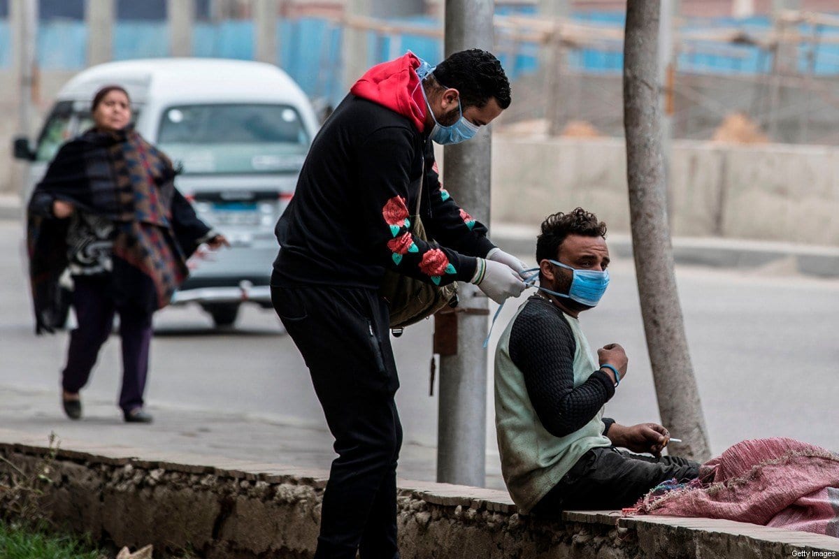Um voluntário (esq) prende máscara de um homem em rua da capital egípcia, Cairo, em 20 de março de 2020 [Khaled Desouki/ AFP/ Getty Images] 