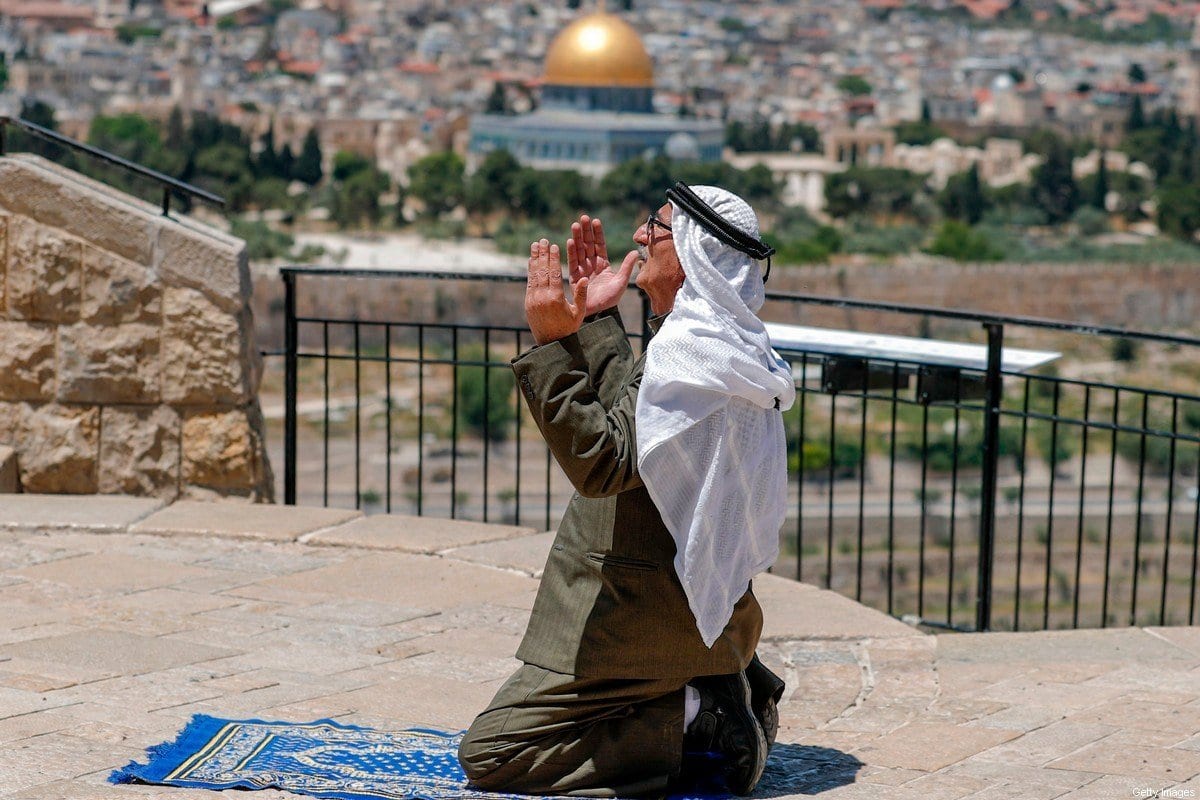 Idoso palestinos realiza oração de sexta-feira durante o mês sagrado do Ramadã, com a Cidade Velha de Jerusalém ao fundo, diante da crise do coronavírus, conforme fechamento do complexo de Al-Aqsa, em 8 de maio de 2020 [Ahmad Gharabli/AFP/Getty Image]