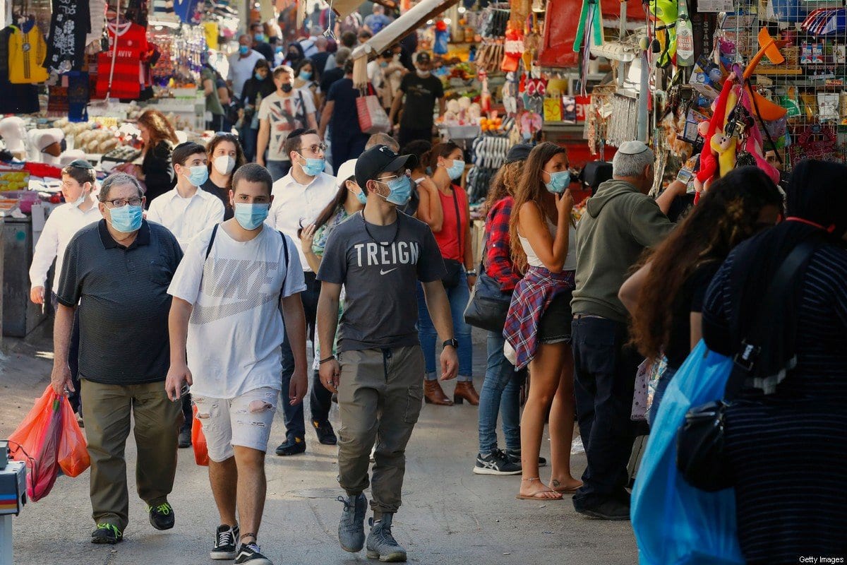 Consumidores com máscaras caminham pelo mercado de Carmelo (Shuk HaCarmel), na cidade israelense de Tel Aviv, em 7 de maio de 2020 [Jack Guez/AFP/Getty Images]