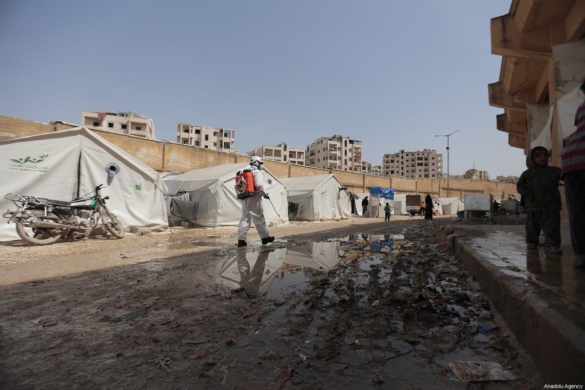 Membros da defesa civil da Síria (Capacetes Brancos) desinfectam tendas habitadas por famílias inteiras, como medida de prevenção contra o coronavírus, em Idlib, Síria, 24 de março de 2020 [Muhammed Said/Agência Anadolu]