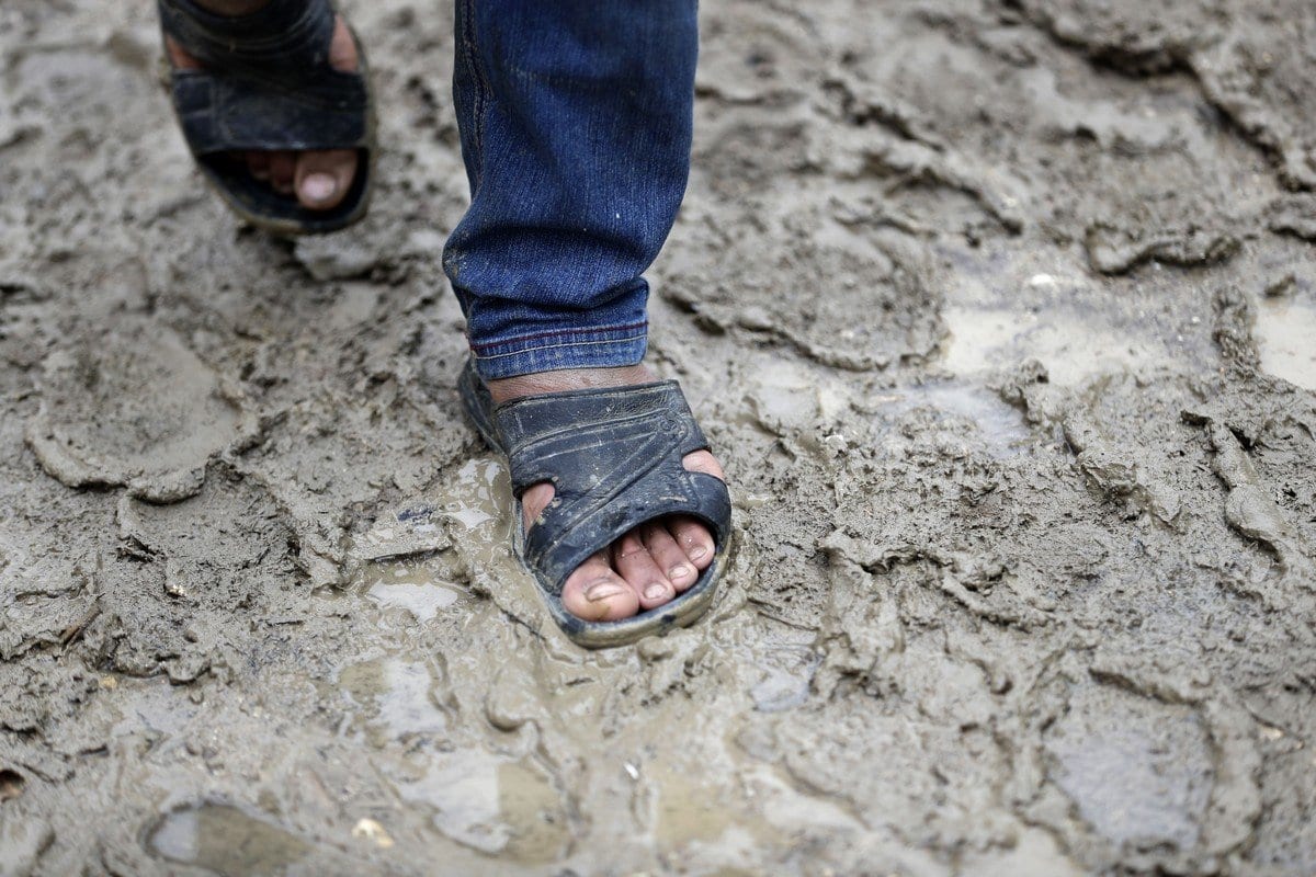 Um garoto sírio caminha pela lama em um beco em um campo de refugiados no Líbano, 10 de julho de 2020 [Joseph Eid/ AFP / Getty Images]