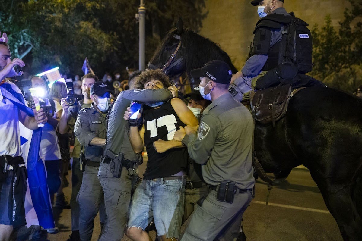 Policiais israelenses prendem manifestante, durante protesto massivo contra o Primeiro-Ministro de Israel Benjamin Netanyahu, reivindicando sua renúncia, sob acusações de corrupção e má gestão da crise do coronavírus, em Tel Aviv, 23 de agosto de 2020 [Mostafa Alkharouf/Agência Anadolu]