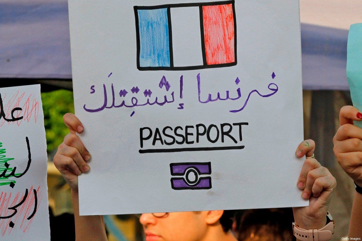 Um manifestante libanês carrega um cartaz que diz em árabe "A França sente sua falta", em referência ao exílio do presidente Michel Aoun na França em 1991, durante uma reunião na cidade de Sidon (Saida), no sul, em 13 de novembro de 2019, quase um mês depois do início um movimento de rua anti-corrupção sem precedentes. [Mahmoud Zayyat/ AFP via Getty Images]