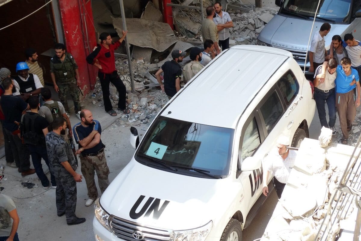Sírios reúnem-se perto de um veículo de especialistas da ONU, que inspecionam o local suspeito de ser atingido por ataque químico mortal, na área de Ghouta Oriental, subúrbios de Damasco, 28 de agosto de 2013 [Mohamed Abdullah/AFP/Getty Images]