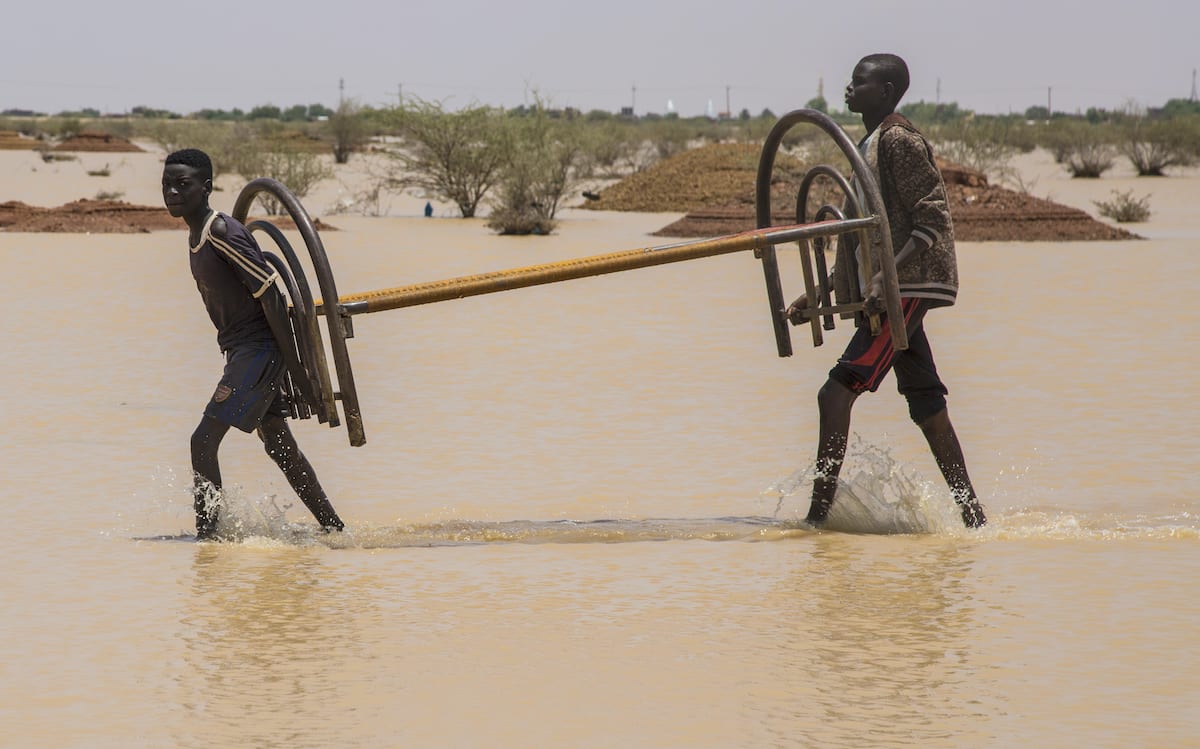 Sudaneses carregam seus pertences em uma área alagada em Cartum, em 03 de agosto de 2020. [Mahmoud Hjaj/ Agência Anadolu]
