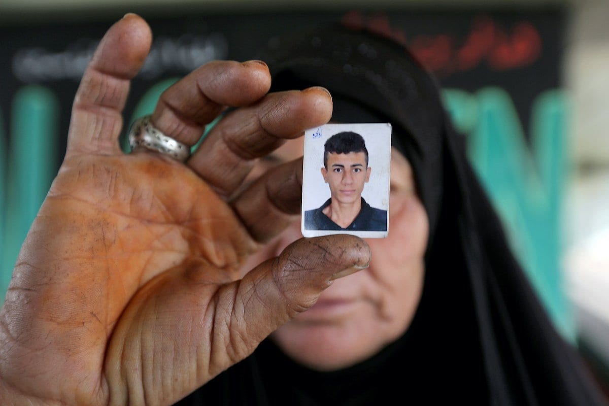 Mulher iraquiana exibe uma foto de seu filho, com quem perdeu, durante protestos contra o governo na Ponte Siniq, em Bagdá, capital do Iraque, 24 de novembro de 2019 [Sabah Arar/AFP/Getty Images]
