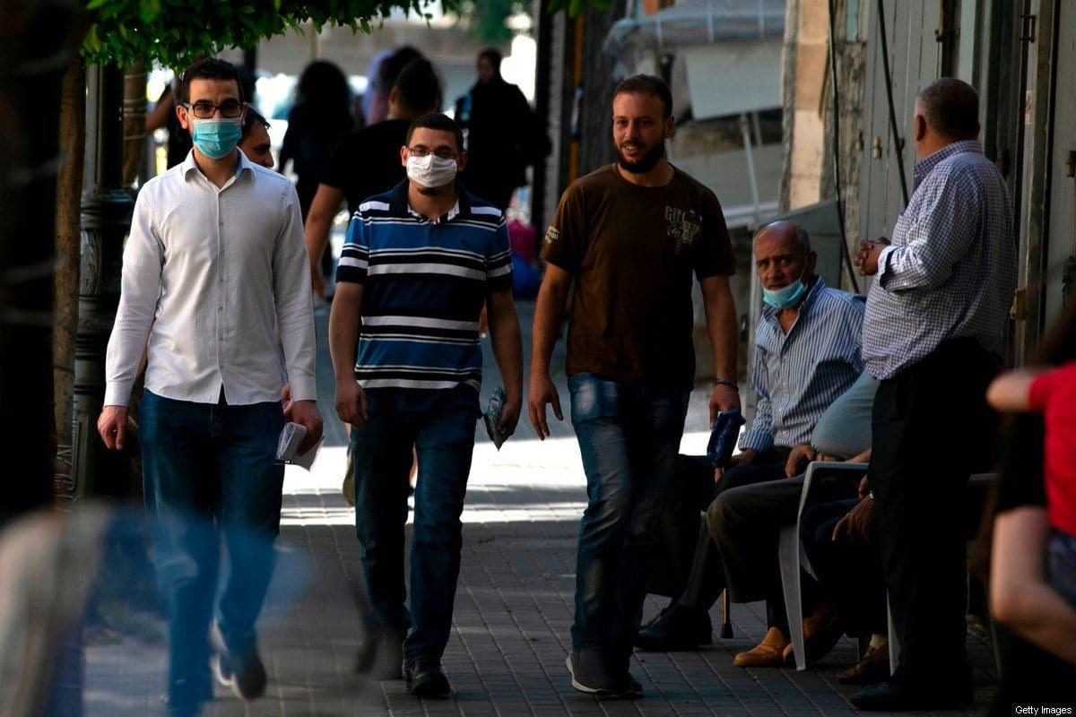 Homens de máscara caminham em Ramallah, Cisjordânia ocupada, durante surto de coronavírus na região, em 13 de julho de 2020 [Abbas Momani/AFP/Getty Images]