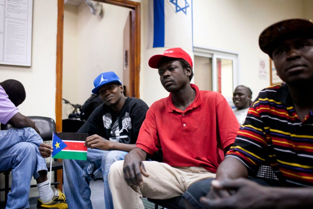 Refugiado do Sudão do Sul segura sua bandeira nacional enquanto é mantido ao lado de outros refugiados em um centro de detenção em Holon, ao sul de Tel Aviv, 11 de junho de 2012. [OREN ZIV / AFP / GettyImages]
