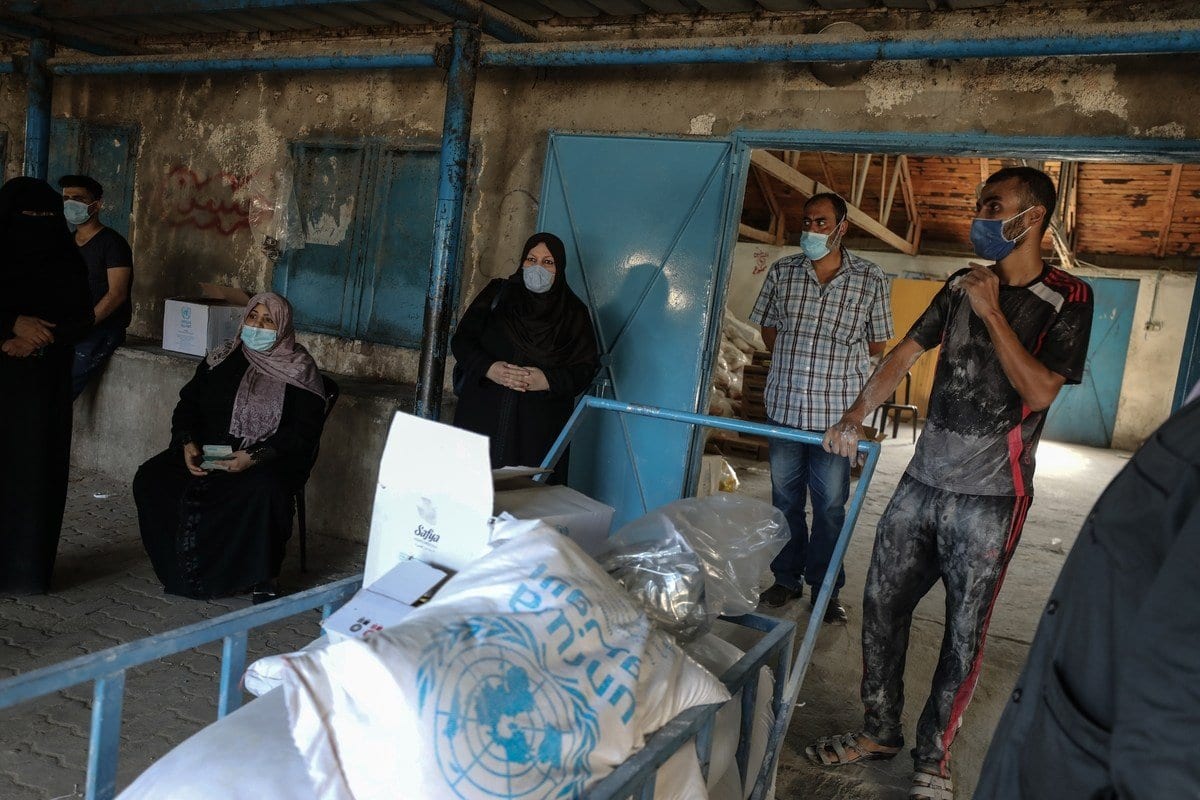 Palestinos recebem alimentos distribuídos pela Agência das Nações Unidas de Assistência aos Refugiados da Palestina (UNRWA), na Cidade de Gaza, 29 de setembro de 2020 [Ali Jadallah/Agência Anadolu]
