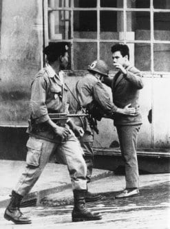 Soldados franceses revistam um civil em uma rua de Argel, durante a Guerra da Independência da Argélia [Central Press / Getty Images]