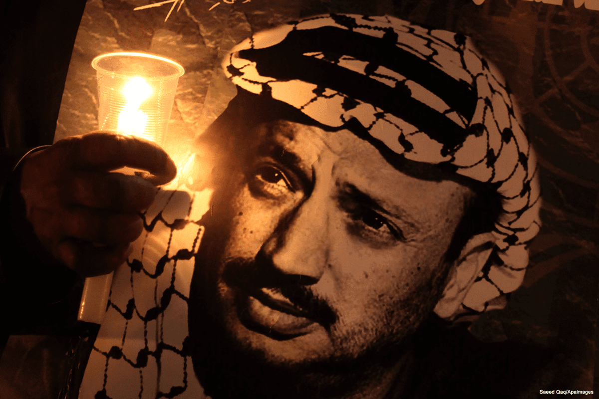 Palestinos seguram cartazes e acendem velas enquanto comemoram a morte do falecido líder palestino Yasser Arafat em 11 de novembro de 2016 [Saeed Qaq / Apaimages]
