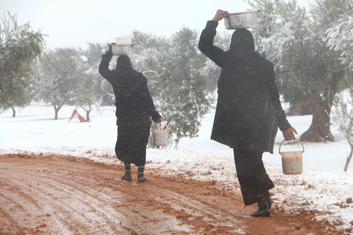 Uma mulher síria caminha com ajuda alimentar em um campo de refugiados na Síria em 21 de dezembro de 2016 [Agência Mamun Ebu Omer/ Agência Anadolu]
