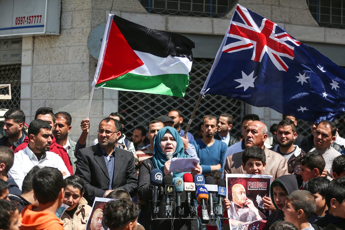 Tehani Zakkut discursa a manifestantes palestinos que exibem cartazes de Mohammad El Halabi, diretor de operações da Visão Mundial Internacional para a Faixa de Gaza, preso por forças israelenses, em ato de 28 de março de 2017 [Mustafa Hassona/Agência Anadolu]
