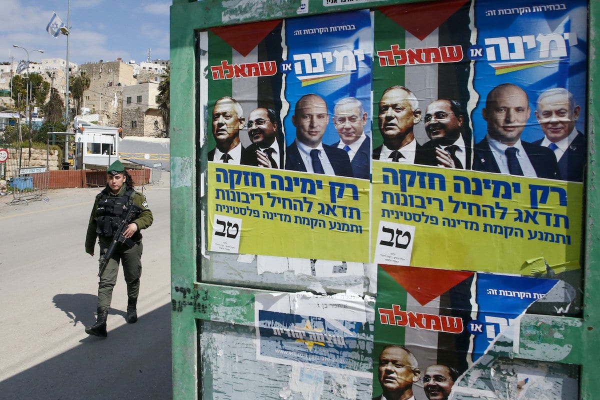 Cartazes eleitorais do líder da aliança política Azul e Branco de Israel (Kahol Lavan) Benny Gantz, exibem o membro árabe-israelense da Lista Conjunta Ahmad Tibi, Ministro da Defesa Naftali Bennett e Primeiro Ministro Benjamin Netanyahu, em Hebron em 23 de fevereiro de 2020 [Haze,Bader/ AFP via Getty Images]
