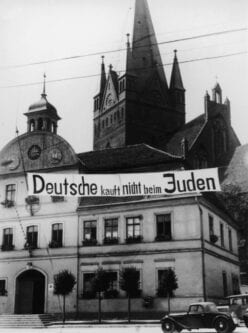 Faixa com os dizeres ‘Deutsche, kauft nicht beim Juden’ (‘Alemães, não comprem dos judeus’) em frente à Sinagoga de Fasanenstrasse, em Berlim, cerca de 1937. O local foi incendiado pelos nazistas durante a Noite dos Cristais, em 9 de novembro de 1938 [Anthony Potter Collection/Getty Images]
