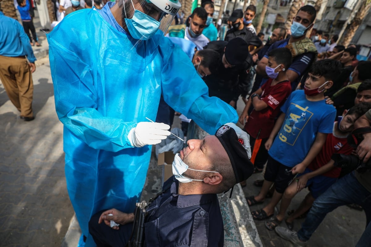 Profissionais do Ministério da Saúde de Gaza coletam amostras de residentes palestinos para testagem do novo coronavírus, no campo de refugiados de Jabalia, Cidade de Gaza, 30 de outubro de 2020 [Ali Jadallah/Agência Anadolu]