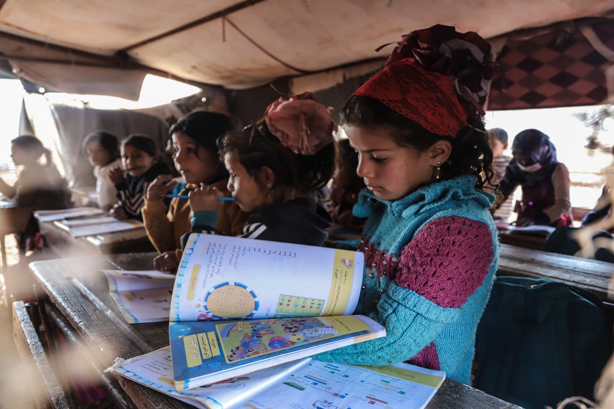 Crianças assistem aula em uma tenda improvisada em um campo de refugiados na Síria, 24 de novembro de 2020 [Muhammed Abdullah/Agência Anadolu]