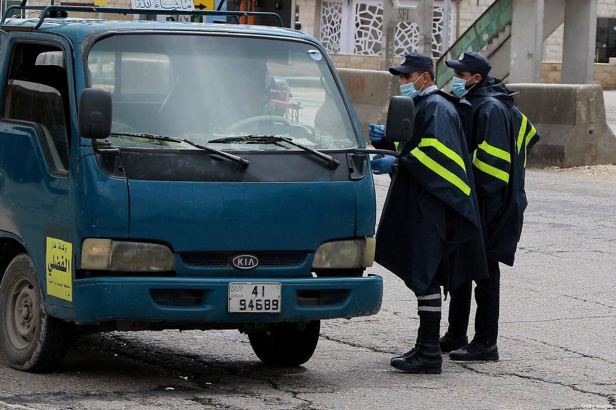 Policiais questionam um motorista em um posto de controle, durante o período de toque de recolher instituído para conter a propagação do coronavírus, em Amã, Jordânia, 21 de março de 2020 [Khalil Mazraawi/AFP/Getty Images]
