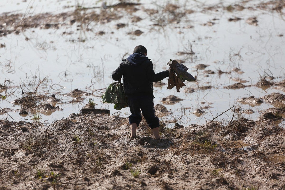 Menino palestino caminha sobre a lama, após forças israelenses abrirem depósitos de águas pluviais sobre terras de Gaza, em 15 de janeiro de 2020 [Mohammed Asad/Monitor do Oriente Médio]
