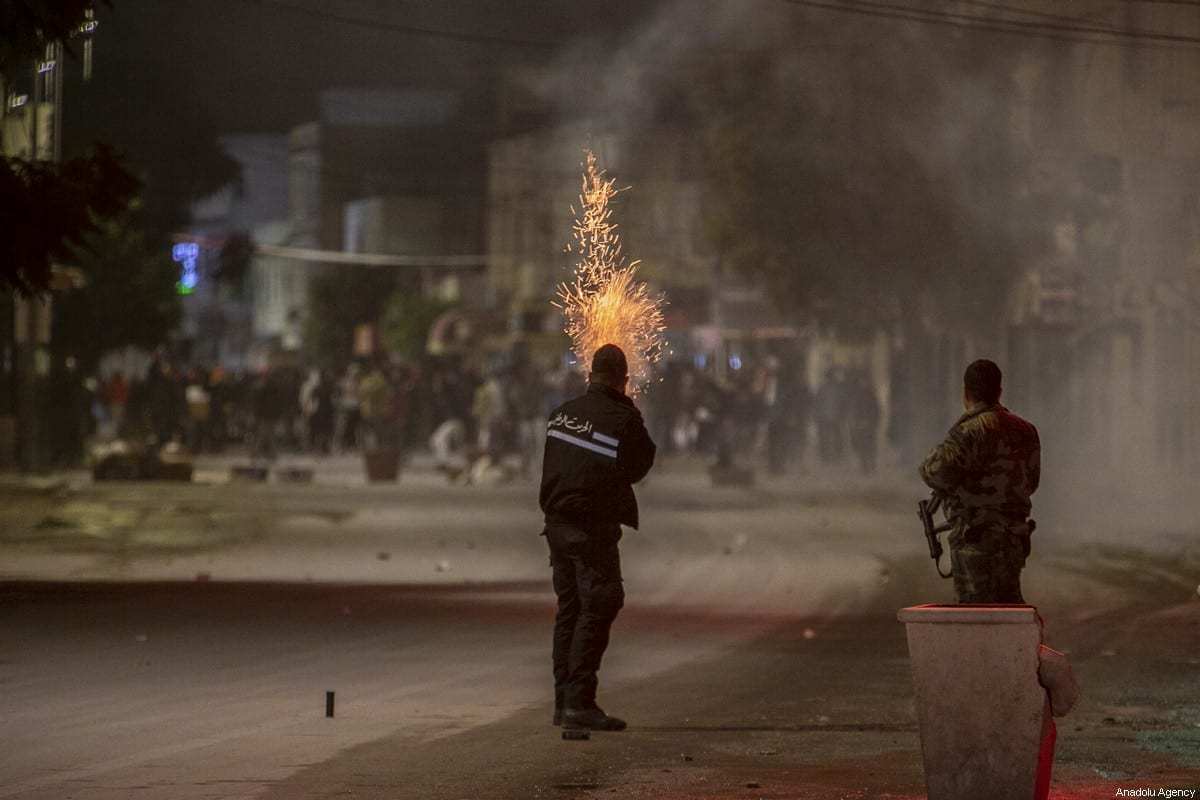 Manifestantes tunisianos entram em confronto com policiais enquanto violam o toque de recolher imposto para conter a pandemia do coronavírus, durante um protesto contra as condições de vida e o desemprego no distrito de At-Tadaman na capital Túnis, Tunísia, em 15 de janeiro de 2021. [Yassine Gaidi/Agência Anadolu]
