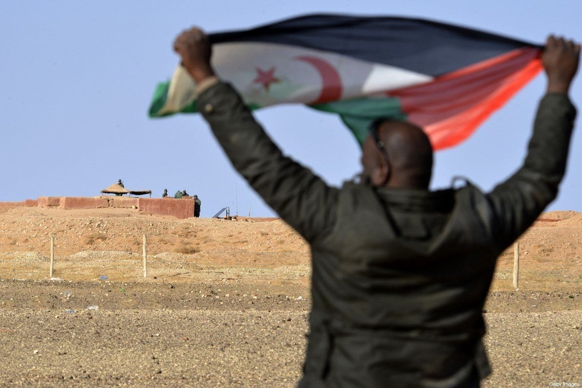 Homem saarauí exibe uma bandeira da Frente Polisário perto do muro que separa o Saara Ocidental do Marrocos, em 3 de fevereiro de 2017 [Stringer/AFP/Getty Images]
