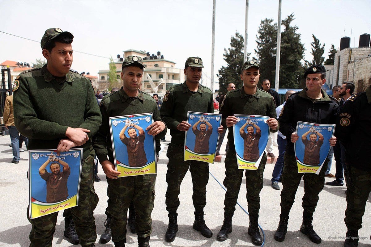 Membros da segurança palestina seguram foto do ativista palestino Marwan Barghouti em 15 de abril de 2015. [Shadi Hatem/Apaimages]