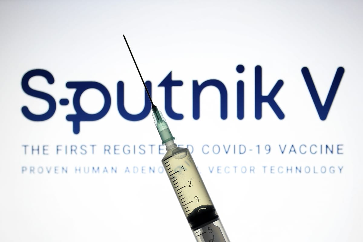 Sputnik V, (Gam-COVID-Vac), o logotipo da vacina da covid-19 é exibido em uma tela com uma seringa na frente. [Hakan Nural/Anadolu Agency]