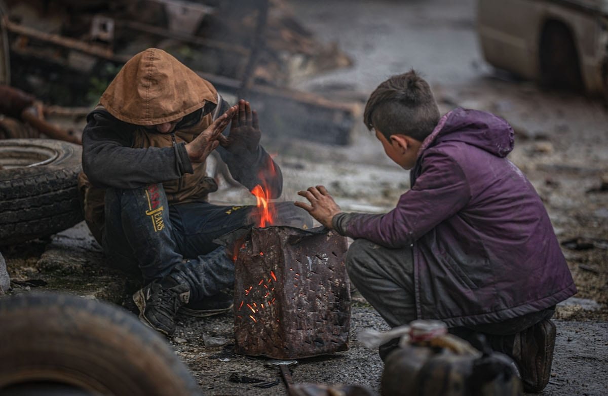 Crianças sírias tentam se aquecer durante o inverno de Idlib, em 30 de janeiro de 2021 [Muhammad Said/Agência Anadolu]