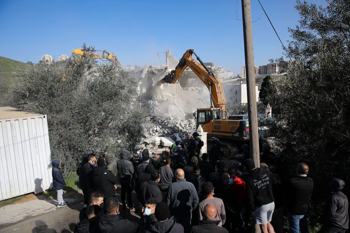 Uma visão do local com a equipe israelense do Município de Jerusalém, juntamente com a polícia israelense e escavadeiras demolindo o prédio de dois andares de propriedade de Fadi Ali Oleyyan, chefe do departamento de segurança da Mesquita de Al-Aqsa, perto de al-Issawiya, bairro que não estava licenciado, em Jerusalém Oriental, em 22 de fevereiro de 2021. [Mostafa Alkharouf/Anadolu Agency]
