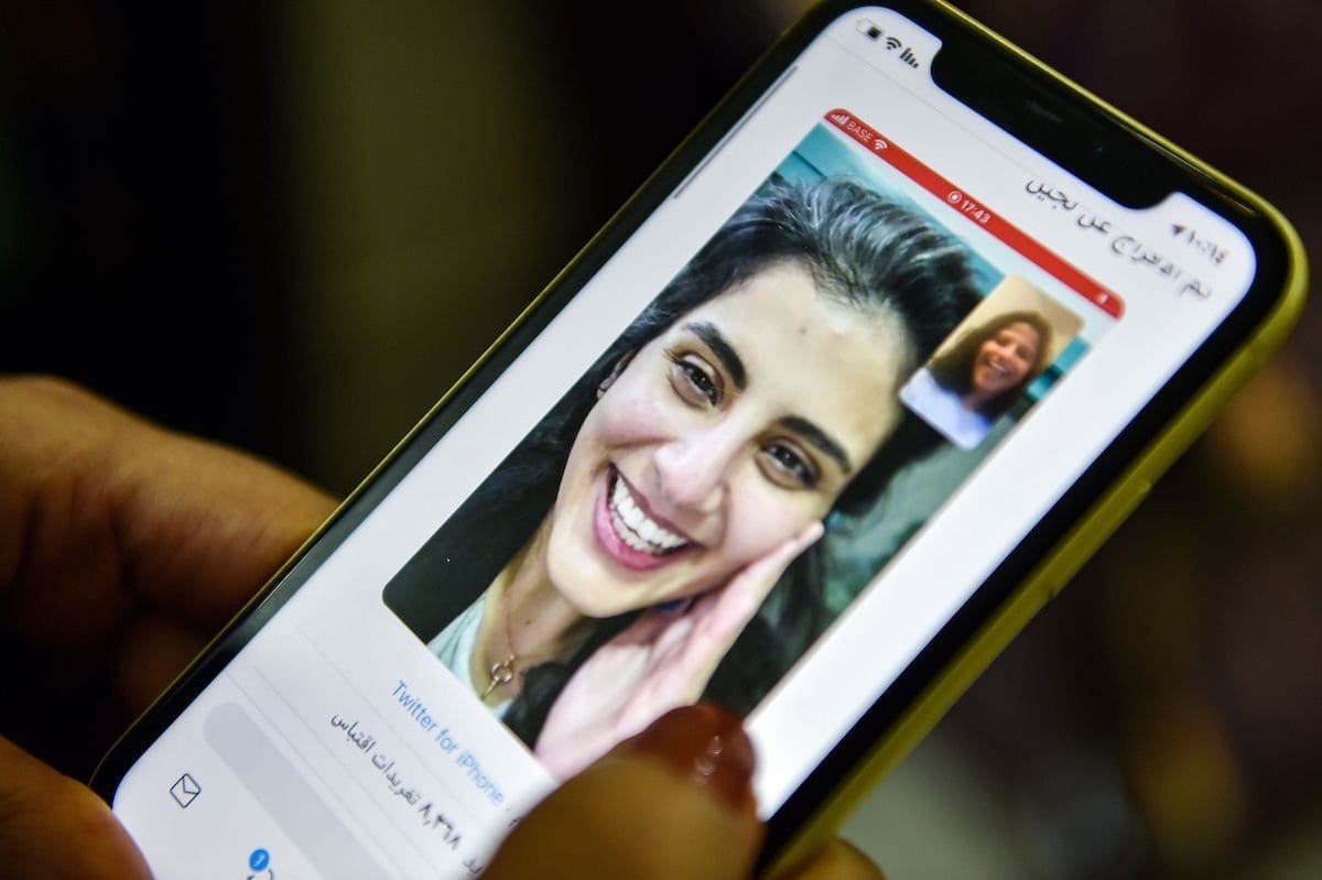 Esta foto, tirada em 10 de fevereiro de 2021 na capital da Arábia Saudita, Riad, mostra uma mulher visualizando um tweet postado pela irmã da ativista saudita Loujain al-Hathloul, Lina, mostrando uma captura de tela delas tendo uma videochamada após a libertação de Hathloul após quase três anos de detenção. [Fayez Nureldine/AFP via Getty Images]
