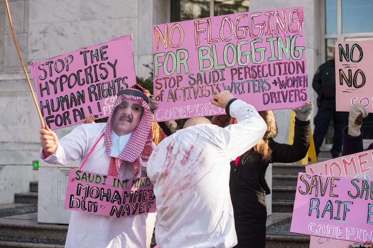 Os manifestantes simulam um açoite em frente à embaixada saudita em Washington, DC, em 15 de janeiro de 2015. [Nicholas Kamm/AFP via Getty Images]
