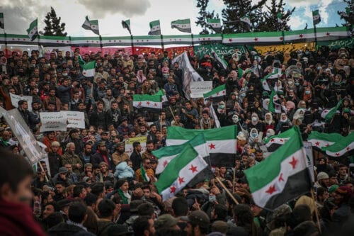 Sírios realizam uma manifestação contra o regime de Bashar al-Assad quando a guerra civil síria entra em seu 11º ano em Idlib, Síria, em 18 de março de 2021. Os manifestantes carregam faixas com os dizeres "A revolução não acabou" e "A vitória é breve". (Muhammed Said/Agência Anadolu)