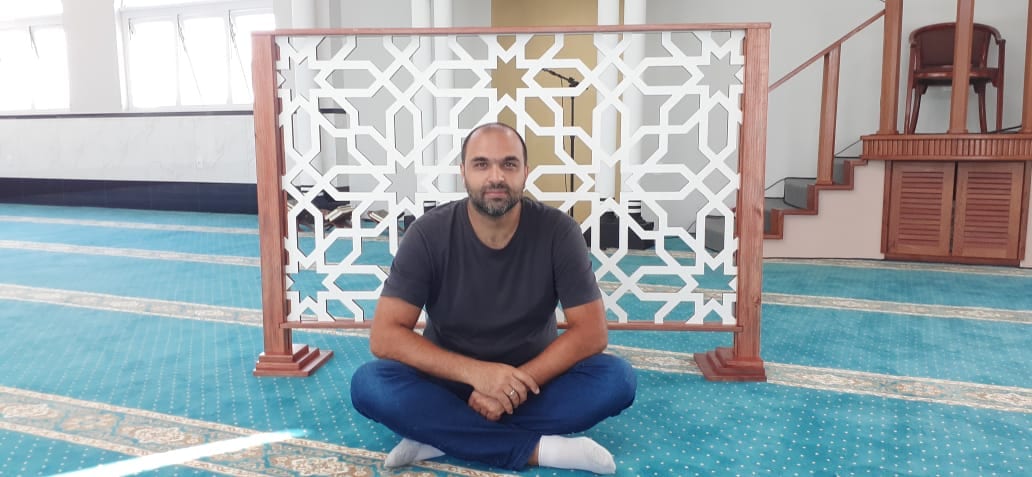 Hani Hussein na mesquita com o “divisor de ambiente” produzido por ele em MDF. [Foto arquivo pessoal]
