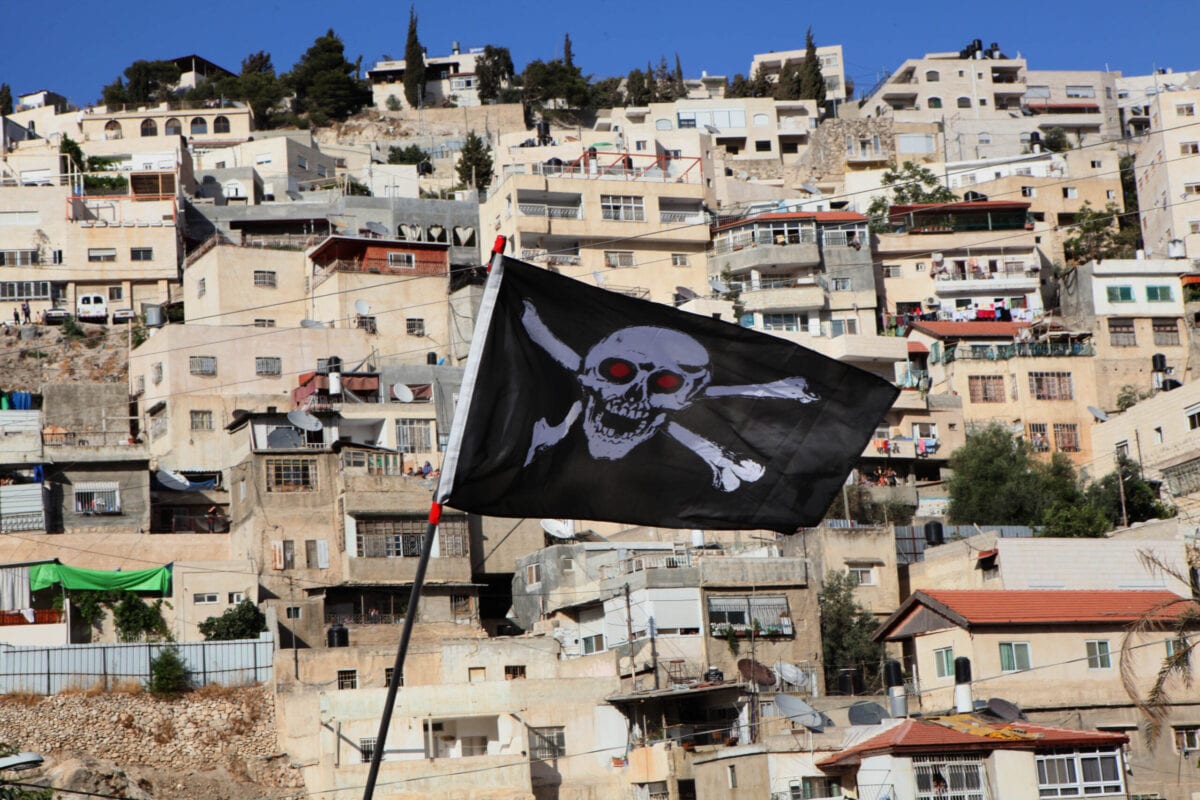 Bandeira erguida em manifestação de ativistas de esquerda,  palestinos e israelenses contra o plano do Município de Jerusalém de demolir 22 casas árabes na área de Al-Bustan de Jerusalém Oriental em 25 de junho de 2010 [Gali Tibbon/ AFP via Getty Images]