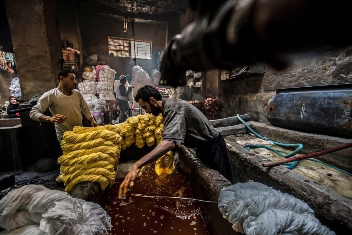 Trabalhadores tingem tecidos em uma oficina manual no distrito histórico de Darb al-Ahmar, Cairo, capital do Egito, em 21 de janeiro de 2020 [Khaled Desouki/AFP via Getty Images]

