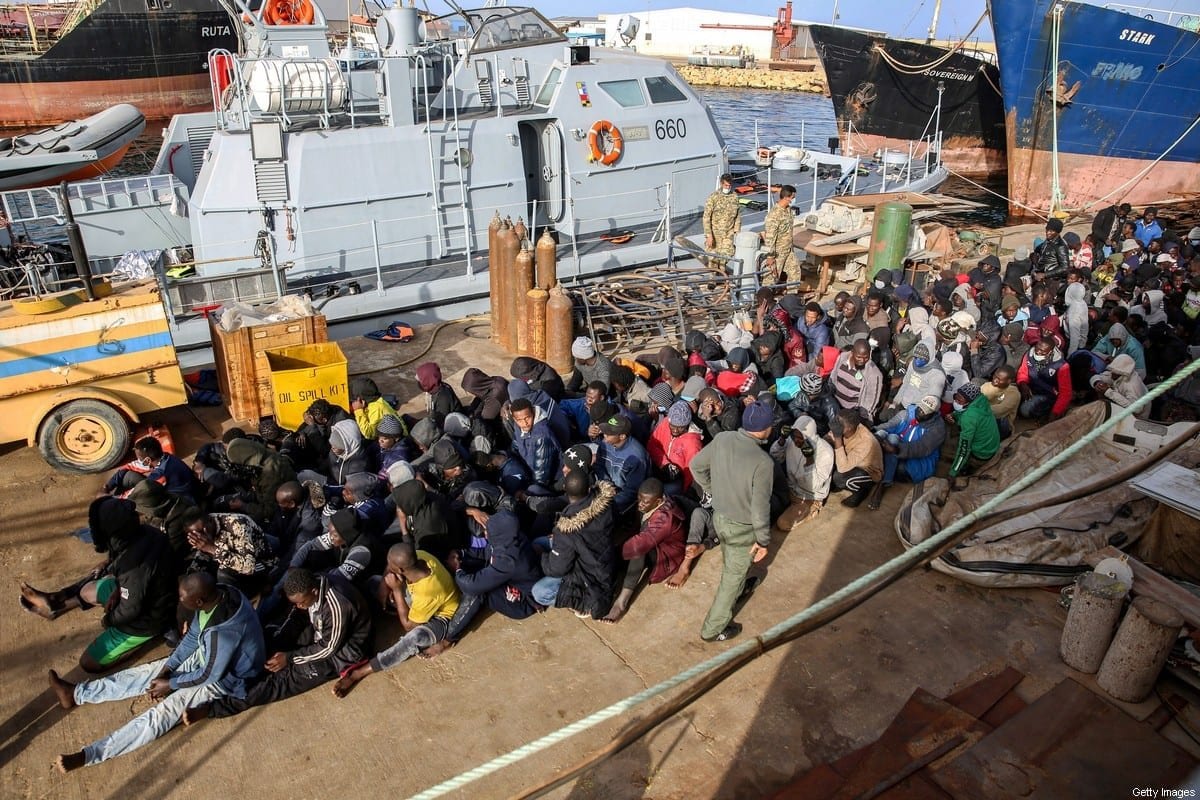 Refugiados resgatados na costa de Al-Khums, cerca de 120 km da capital, sentam-se no píer da base naval de Trípoli, Líbia, 10 de fevereiro de 2021 [AFP via Getty Images]