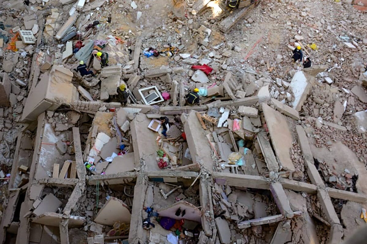 Voluntários e profissionais de resgate buscam sobreviventes nos escombros de um edifício no bairro de Gesr Suez, zona leste do Cairo, capital do Egito, em 27 de março de 2021 [AFP via Getty Images]
