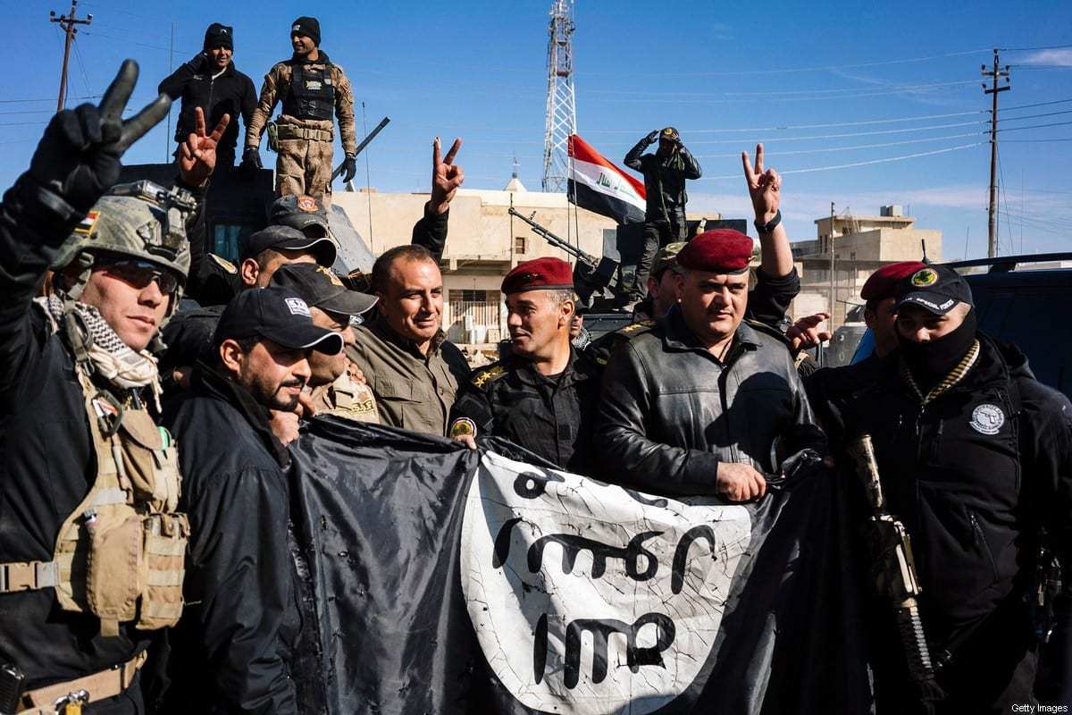 Membros do Serviço de Contraterrorismo do Iraque exibem uma bandeira do Estado Islâmico (Daesh) para celebrar uma vitória militar contra o grupo terrorista [Dimitar Dilkoff/AFP via Getty Images]