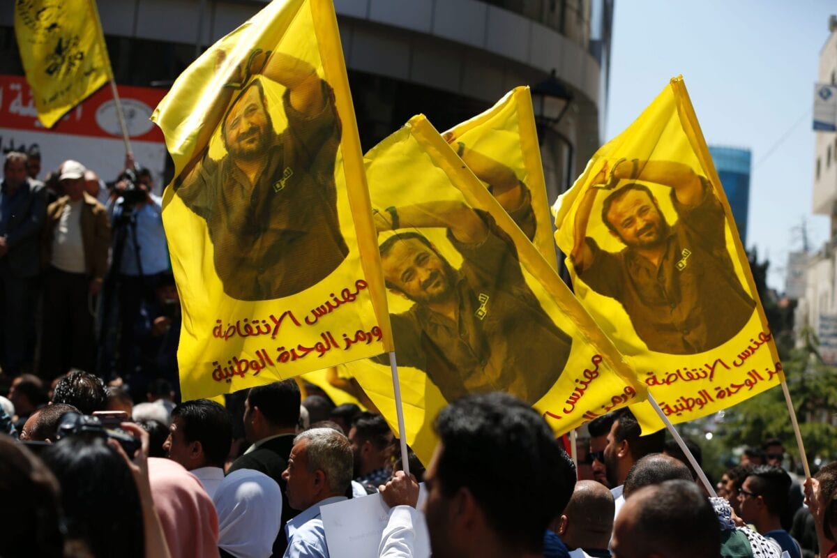 Manifestantes agitam bandeiras com um retrato do palestino Marwan Barghouti durante um manifestação na cidade de Ramallah, na Cisjordânia, em 17 de abril de 2017 [Abbas Momani/ AFP via Getty Images]
