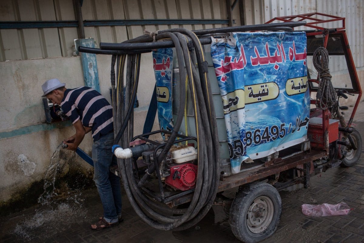 Um homem desconecta uma mangueira de seu caminhão-pipa após reabastecer em um depósito de água em 20 de julho , 2017 na cidade de Gaza, Gaza [Chris McGrath / Getty Images]
