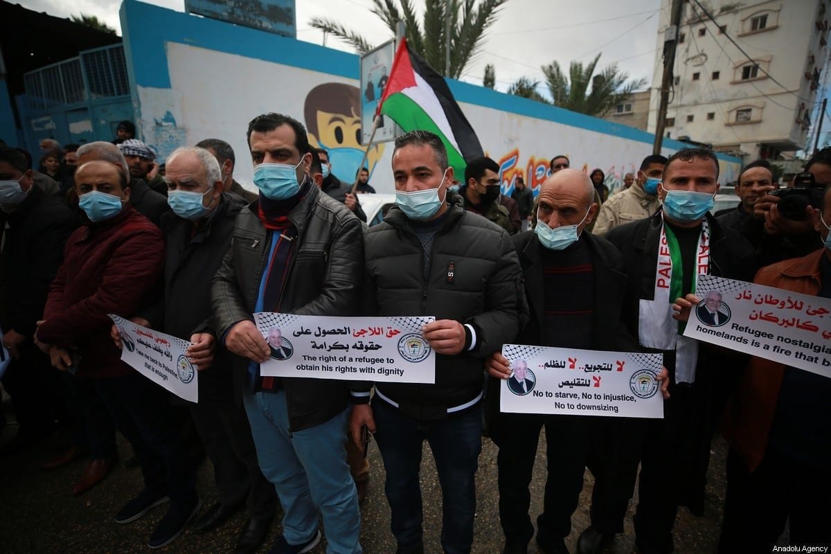 Palestinos seguram cartazes durante um protesto contra os cortes de ajuda alimentar pela Agência das Nações Unidas de Assistência e Obras (UNRWA), fora da UNRWA em Khan Yunis, Gaza em 20 de janeiro de 2021. [Mustafa Hassona/Agência Anadolu]
