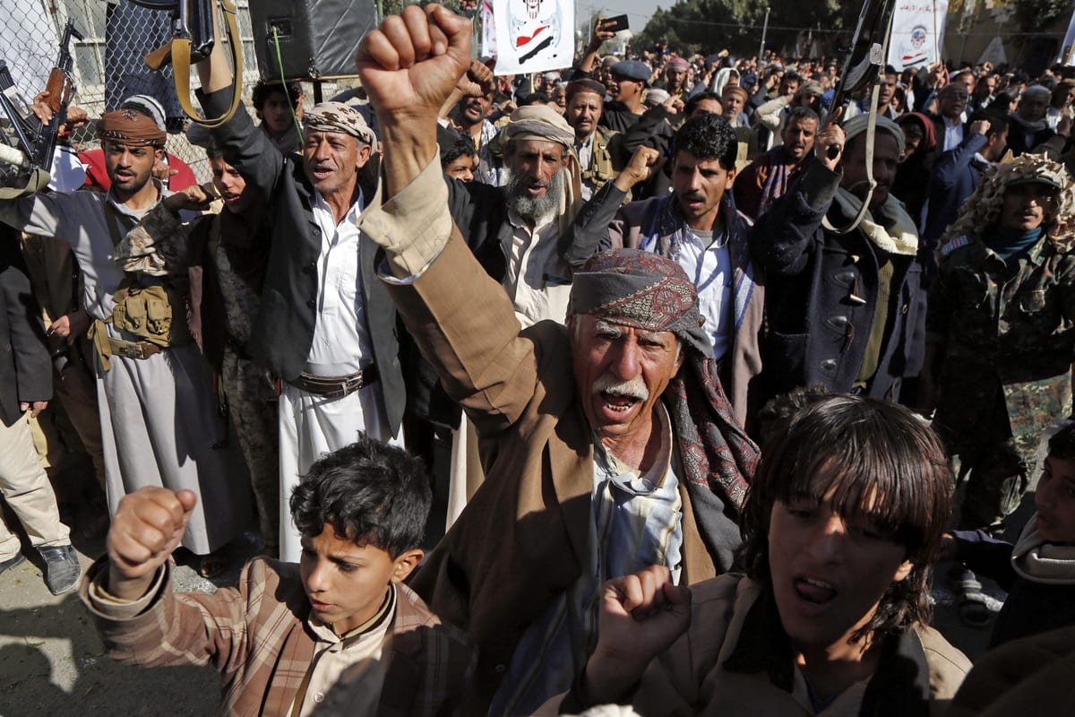 Apoiadores do movimento iemenita houthi erguem os punhos e entoam palavras de ordem durante manifestação em frente à antiga embaixada dos Estados Unidos em Sanaa, capital do Iêmen, em 18 de janeiro de 2021 [Mohammed Hamoud/Agência Anadolu]
