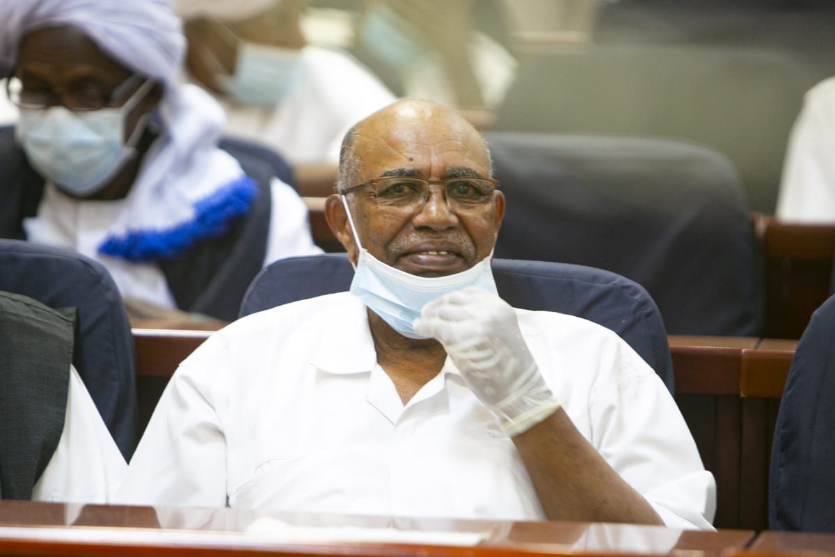 O presidente deposto do Sudão, Omar al-Bashir, aparece durante seu julgamento junto com outros sobre o golpe militar de 1989 que os levou ao poder, no tribunal especial estabelecido no Instituto de Treinamento de Oficial na capital, Cartum, em 2 de fevereiro de 2021. [Mahmoud Hjaj/Agência Anadolu]