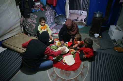 Família síria reúne-se para romper o jejum no primeiro dia do Ramadã, no campo de refugiados de Ma’arrat Misrin, em Idlib, Síria, 13 de abril de 2021 [Ahmet Karaahmet/Agência Anadolu]