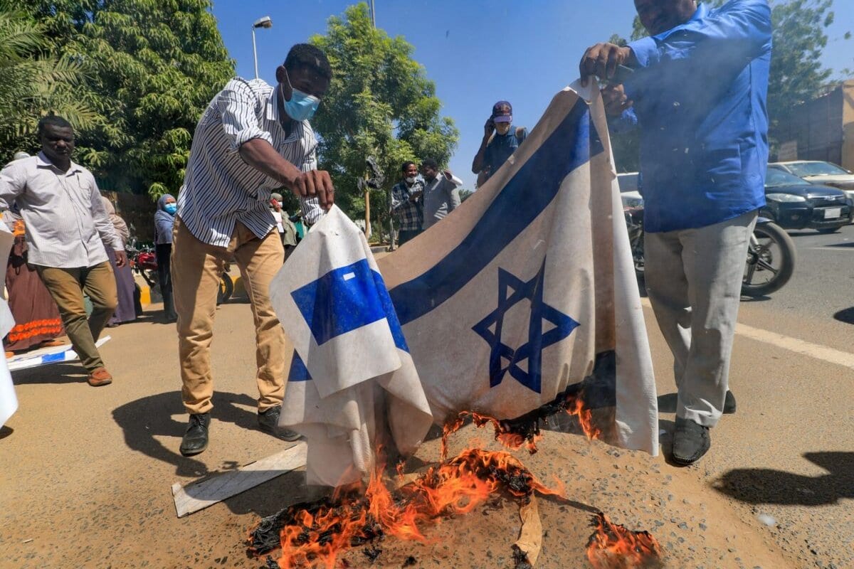   Manifestantes sudaneses queimam uma bandeira israelense em 17 de janeiro de 2021 [Ashaf Shazly/ AFP via Getty Images]