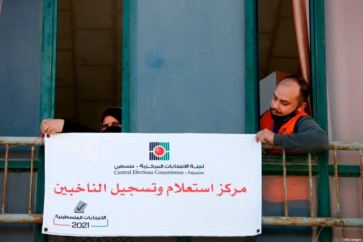 Membros da Comissão Eleitoral Central Palestina penduram um placa em árabe "centro de informações e registro de eleitores" na cidade de Hebron, na Cisjordânia, em 10 de fevereiro de 2021 [Hazen Bader/ AFP via Getty Images]