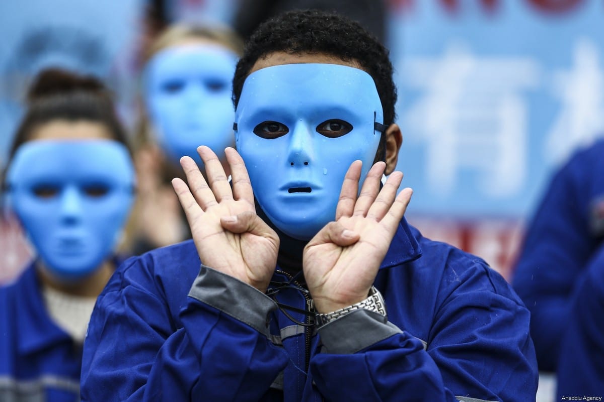 Manifestantes usam máscaras durante um protesto contra as políticas e opressões do governo chinês contra os uigures em frente à embaixada chinesa em Berlim, Alemanha, em 23 de janeiro de 2021 [Abdulhamid Hoşbaş/Agência Anadolu]

